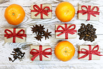 gift packages wrapped in gray paper with organic red ribbon, nectarines and anise on the wooden background;