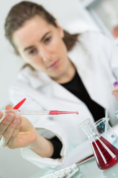 scientist with pipette and test tube examining samples in laboratory