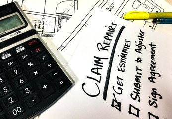Insurance Claim papers and estimates on desk with calculator 