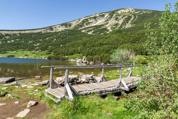 Fototapeta premium Landscape with wooden bridge over river in Pirin Mountain, Bezbog lake and peak, Bulgaria
