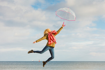 Woman jumping with transparent umbrella on beach