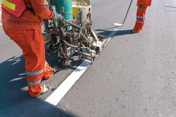 Thermoplastic spray marking machine during road construction.
Worker painting white line on the...