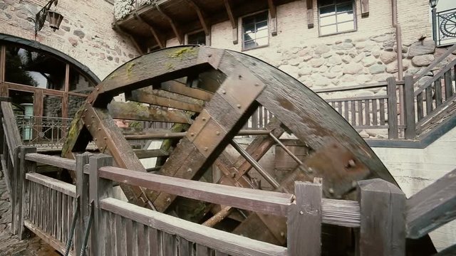 A big old watermill is working noisily inside a castle yard