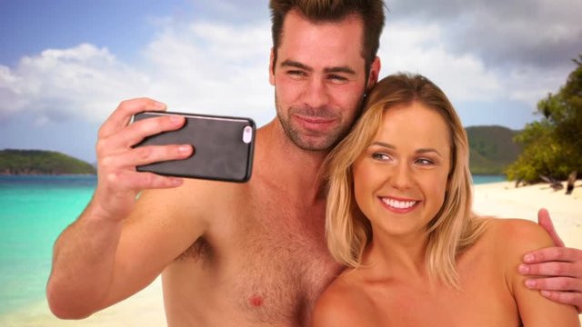 Happy millennial couple taking pictures with smartphone at the beach