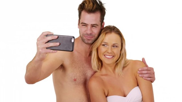 Happy millennial couple taking pictures with smartphone at the beach