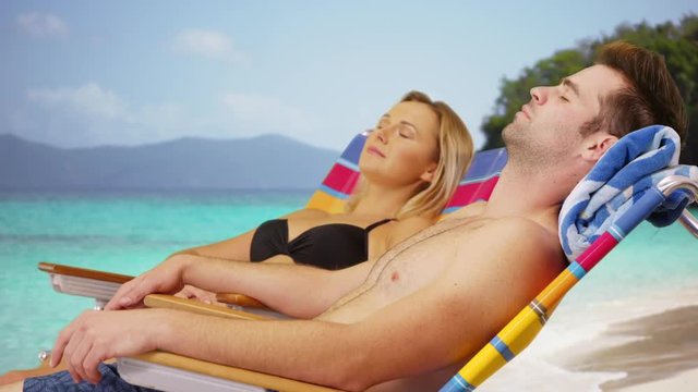 White millennial couple relaxing under the sun at the beach