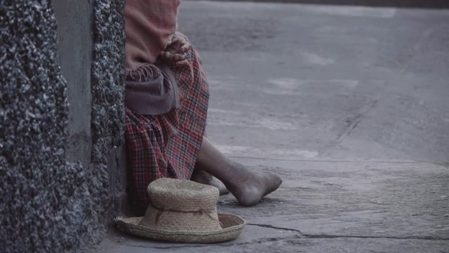Detail of woman seated on the street, barefoot, poverty in Latin America.