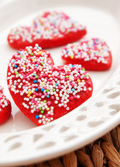 Homemade heart-shaped red cookies decorated with colorful sprink