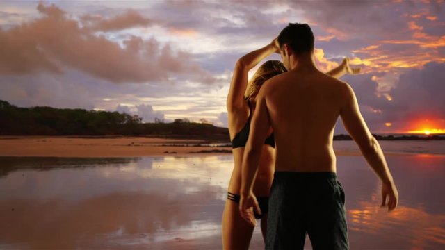 Silly millennial couple dancing together at the beach during sunset