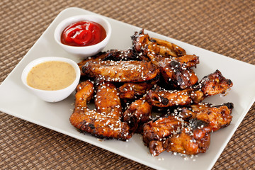 Baked chicken wings with barbecue sauce, sesame seeds, mustard a