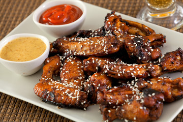 Baked chicken wings with barbecue sauce, sesame seeds, mustard a