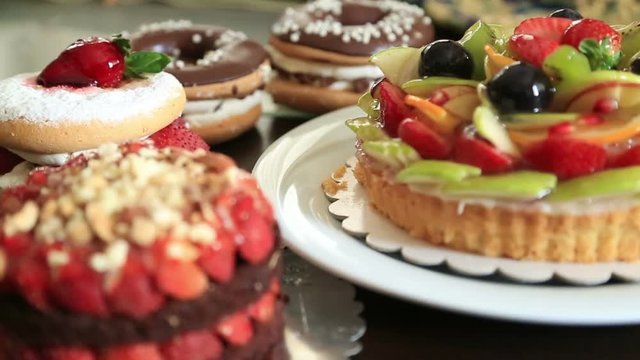 Assorted fruit tartlets, donuts and pieces of cakes