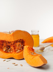 cut pumpkin and honey on a light wooden background