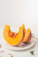 Fototapeta na wymiar raw chopped pumpkin on white wooden background
