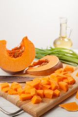 raw chopped pumpkin on white wooden background