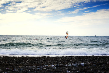 Group of windsurfers on boards in wavy sea