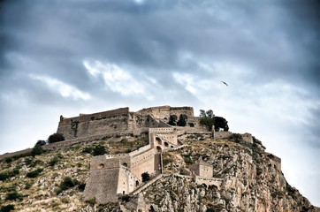 Fototapeta na wymiar Palamidi fortress on the hill,under a cloudscape and a seagull flying above it. Nafplion - Greece