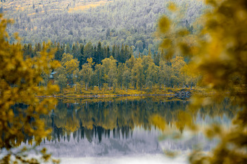 Rocky shore of mountain lake in misty autumn morning. Beautiful nature Norway. Reflection on the lake