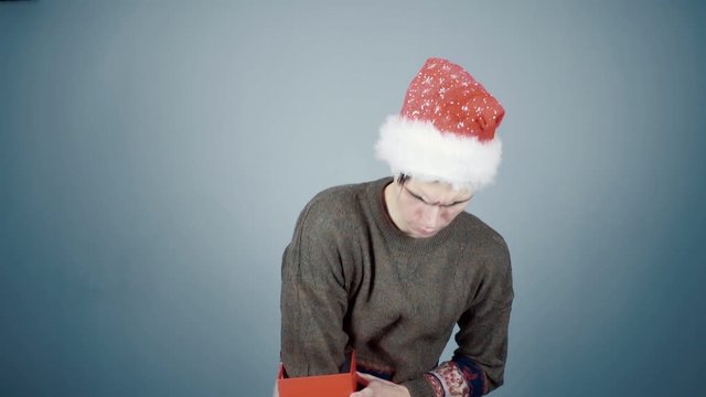 Young man in Santa hat opening a gift box with a surprise pulls out long necklace
