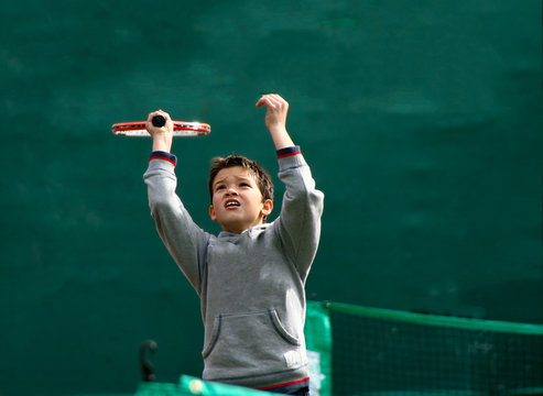 Little tennis player on a blurred green background