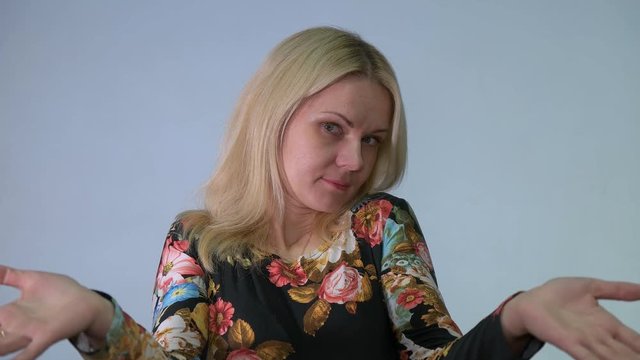 Shocked blonde woman spreads hands apart