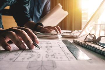 Two colleagues discussing data working and tablet, laptop with on on architectural project at construction site at desk in office
