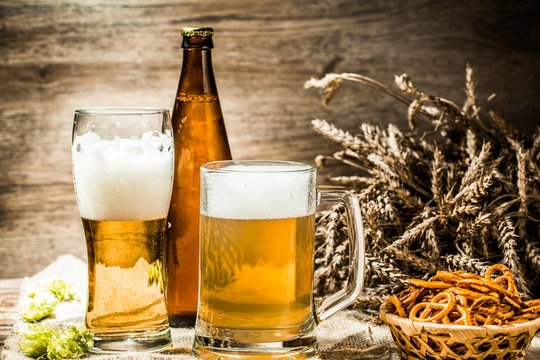 Mug, glasse, bottle of beer with foam on wooden table
