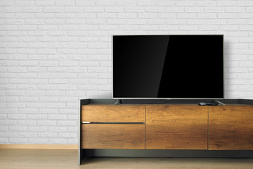 Led TV on TV stand in empty room with white brick wall. decorate in loft style.