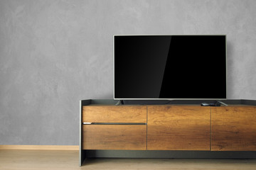 Led TV on TV stand in empty room with cement wall. decorate in loft style.