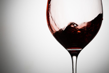 Red wines wave flows down the wall of wineglass closeup