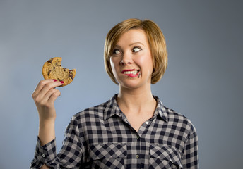  cute beautiful woman with chocolate stain in mouth eating big delicious cookie