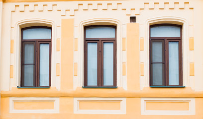 Fototapeta na wymiar Three historic brown window on the yellow wall