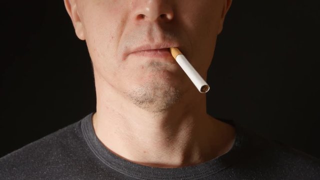 Face of young adult man who takes a few cigarettes in his mouth