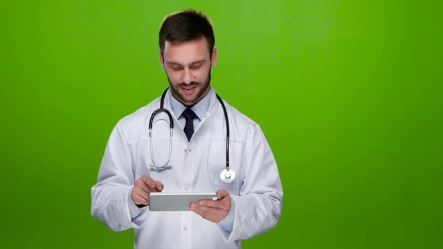 Young doctor looks at pictures on the tablet pc. Green screen