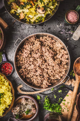 Minced Meat in cooking pot on rustic kitchen table with ingredients , rice and cooked cabbage, top view