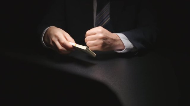 Bribe: Businessman takes a money bundle from a table and puts in a suit at negotiation time (US dollar)