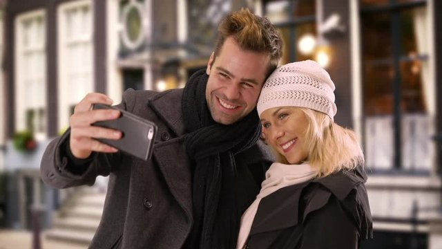 Happy yuccie couple taking selfies outdoors during winter time