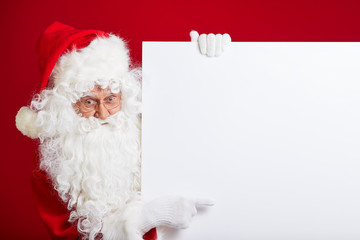 Santa Claus pointing in blank advertisement banner isolated on r