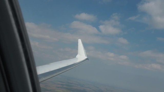 Wing of an airplane flying above the clouds. View of the sky from the window of the plane. The picture of the blue sky and airplane's wing. Foto of the airplain moving through the heaven.