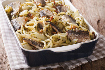 Spaghetti with sardines, fennel, raisins, nuts and parsley close up in baking dish. horizontal