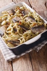 Italian food: pasta with sardines, fennel, raisins and pine nuts close up in baking dish. vertical