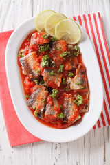 Braised sardines in tomato sauce with lime and parsley close-up. vertical top view