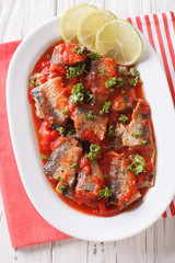 Tasty sardines in tomato sauce with lime and parsley close-up. vertical top view