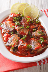 Braised sardines in tomato sauce with lime and parsley close-up. Vertical