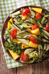 salad of mango, avocado, kiwi, lettuce, tomato dressed with balsamic sauce closeup. vertical top view