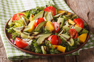 Tasty salad of mango, avocado, kiwi, lettuce, tomato close-up on a plate. horizontal