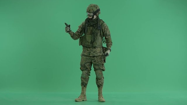 combatant holding a gun at the green screen back ground