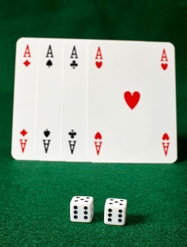 White dices and four aces  on green table.Ιllegal gambling.