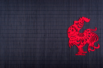 Silhouette of rooster on black bamboo mat