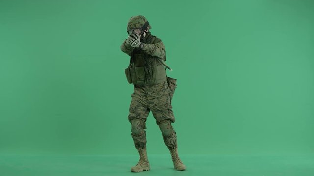 Soldier standing and targeting around with pistol at green screen
